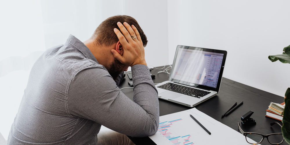 Stressed IT professional reviewing error reports on a laptop during the AWS outage, highlighting the operational impact of cloud service disruption.